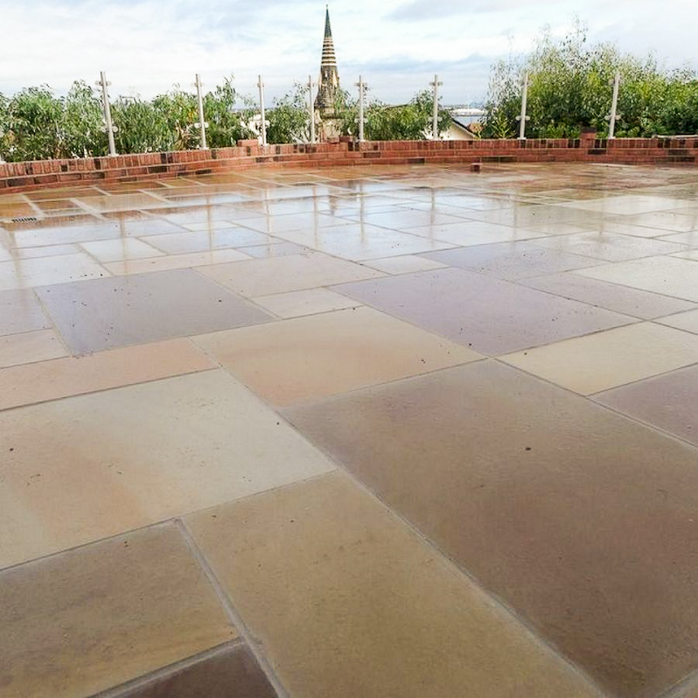 Rippon Sawn & Honed Sandstone as a finished patio wet low level image with brick wall in the background